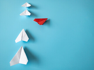 Wall Mural - Red paper plane origami leaving other white planes on blue background. Copy space and leadership skills concept.