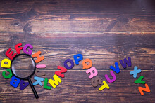 Multicolored English Letters Spread On The Wooden Floor. Magnifier And English Alphabet With English Learning Concepts, The Concept Of Thinking Development, Grammar