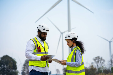 Engineer male and female on wind turbine farm. Two engineers discussed the plan for the maintenance of wind turbines.