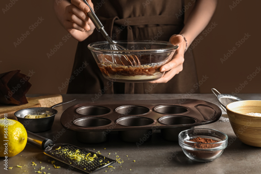 Woman preparing delicious muffins in kitchen