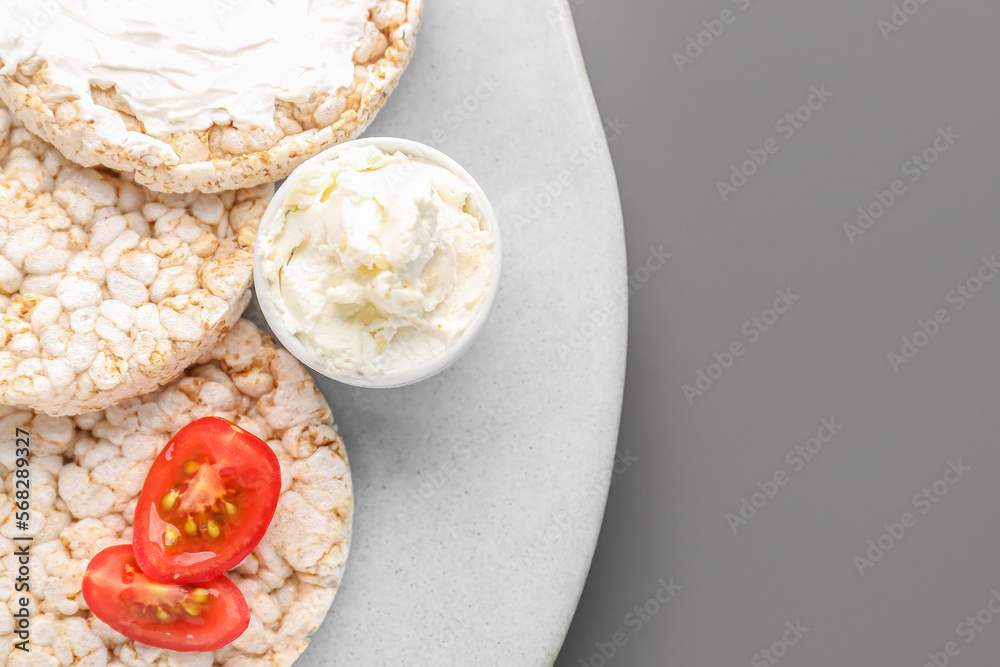 Plate with tasty crispbreads and cream cheese on grey background, closeup