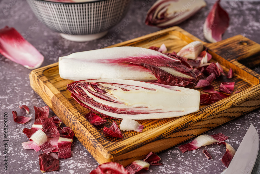 Wooden board with cut red endive on grunge background