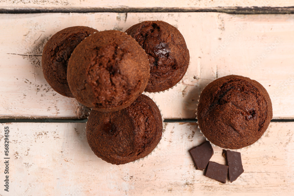 Delicious chocolate muffins on white wooden background