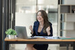 © SOMKID - Joyful Asian businesswoman freelancer entrepreneur smiling and rejoices in victory while sitting at desk in office.