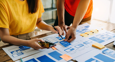  UX developer and ui designer brainstorming about mobile app interface wireframe design with customer breif and color code at modern office..