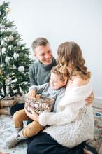 Man Hugs His Wife, Son Holds Basket With Decor For Christmas Tree