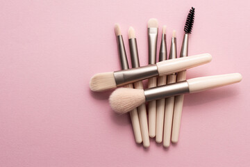 Wall Mural - Set of makeup brushes on soft pink colored background. Top view, flat lay.