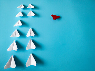 Wall Mural - Red airplane origami leaving other white airplanes on blue background with customizable space for text. Leadership skills concept