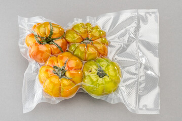 Green tomatoes in vacuum pack for sous vide cooking on gray background