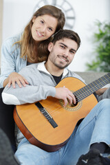 Wall Mural - handsome husband teaching beautiful wife to play acoustic guitar