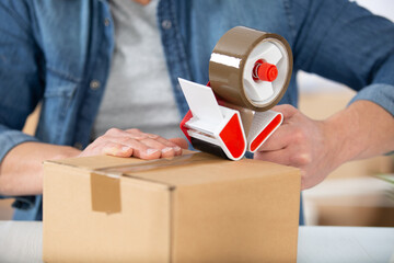 man applying adhesive tape on a packing box