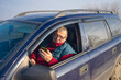 portrait of Caucasian senior  inside his car on short stop on roadside while traveling in Ukraine