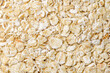 Oat flakes raw, flattened croup in bulk, close-up, background wallpaper, uniform texture pattern