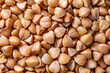 Buckwheat groats raw, small grains in bulk close-up, background wallpaper, uniform texture pattern