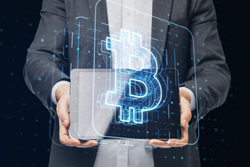 Poster - Close up of businessman hands holding tablet with glowing bitcoin hologram on dark background. Cryptocurrency and crypto market concept.