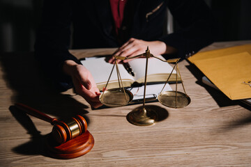 Justice and law concept.Male judge in a courtroom with the gavel, working with, computer and docking keyboard, eyeglasses, on table in morning light