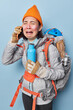 © wayhome.studio  - Upset desperate female tourist expresses negative emotions cries unhappily has unpleasant talk via mobile phone with friend holds thermos with tea carries rucksack has some problems during hiking trip
