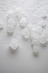 Wall Mural - Ice cubes with water drops scattered on white background. Top view, flat lay