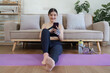 © itchaznong - Healthy asian woman practicing relaxation yoga at home. Spending time and playing phone at home concept