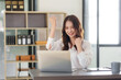 © amnaj - Attractive Asian businesswoman raising hands happily with successful plan with happy smile with laptop computer.