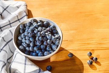 Poster - Fresh organic blueberries. Juicy ripe bilberry in white bowl on wooden table. Antioxidant and healthy eating concept.