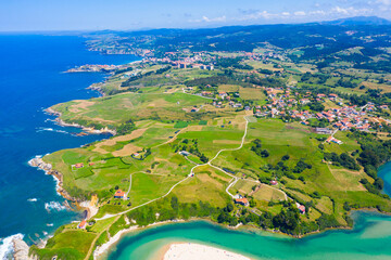 Wall Mural - Aerial panoramic view of summer landscape overlooking small Spanish town of Comillas on coast of Cantabrian Sea..