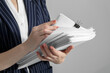 Woman stacking documents on grey background, closeup