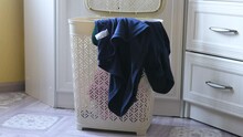 Dirty Clothes And Socks Are Thrown Into The Laundry Basket For Washing In The Home Interior. Daily Routine Housework, Washing Clothes Concept. Dirty Linen Flies Into The Container