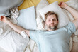 © Westend61 - Man waking up on bed at home