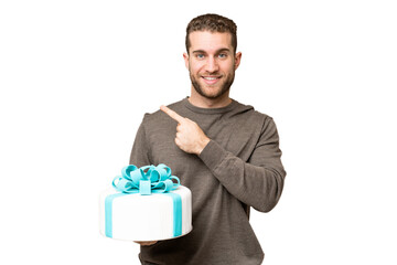 Wall Mural - Young handsome blonde man holding birthday cake over isolated chroma key background pointing to the side to present a product