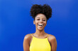 © Westend61 - Young woman with Afro hairstyle laughing over blue background