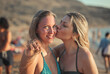 © Cavan Images - young woman kisses her friend at the beach