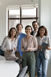 © fizkes - Diverse team of cheerful happy business employees meeting in office, looking at camera, smiling, laughing, celebrating success. Senior female leader, boss, teacher posing with group. Vertical portrait