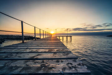 Wall Mural - Rising sun above wooden bridge at sea coast