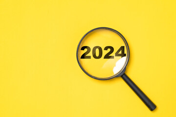 Wall Mural - 2024 year inside of magnifier glass on yellow background for focus and preparation new year change a