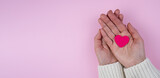 Fototapeta Kwiaty - Woman's hands hold a pink heart on a pink background.Valentine's Day composition. Banner. Place for text. Top view. Selective focus.
