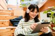 © Drobot Dean - Asian woman using tablet computer and headphones while sitting indoors