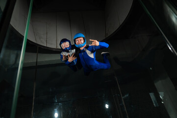 Wall Mural - A man teaches a boy to fly in a wind tunnel. Lack of gravity.