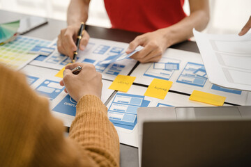 ui designer brainstorming about mobile app interface wireframe design with customer breif and color code at office.