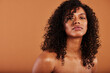 © Flamingo Images - Young black woman with bare shoulders standing against an orange background