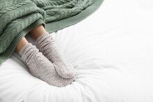 Woman Wearing Warm Socks In Comfortable Bed, Closeup. Space For Text