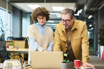 Aufkleber - Mature man and young businesswoman watching online webinar or conference while bending over laptop and looking at screen