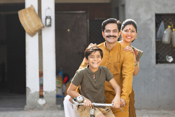 Portrait of happy Indian parents with son riding on bicycle