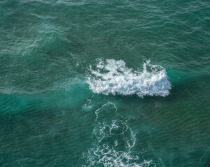 Wall Mural - ocean foamy waves approaching rocky shore. top view.