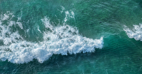 Wall Mural - ocean foamy waves approaching rocky shore. top view.