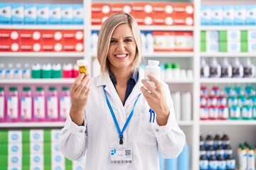 Canvas Print - Young blonde woman pharmacist smiling confident holding pills bottles at pharmacy