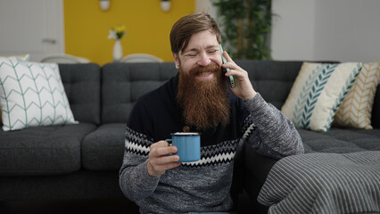 Sticker - Young redhead man talking on smartphone drinking coffee at home