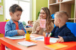 © Krakenimages.com - Teacher with boys sitting on table having language lesson at kindergarten