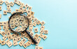 © яна винникова - Square letter tiles with magnifying glass against blue background. Search for words and information concept