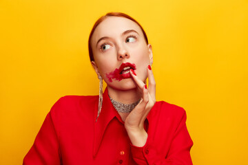 Wall Mural - After eating. Beautiful young girl in red shirt with smudged red lipstick over yellow studio background. Food pop art photography. Complementary colors. Concept of art, beauty, food. Copy space for ad